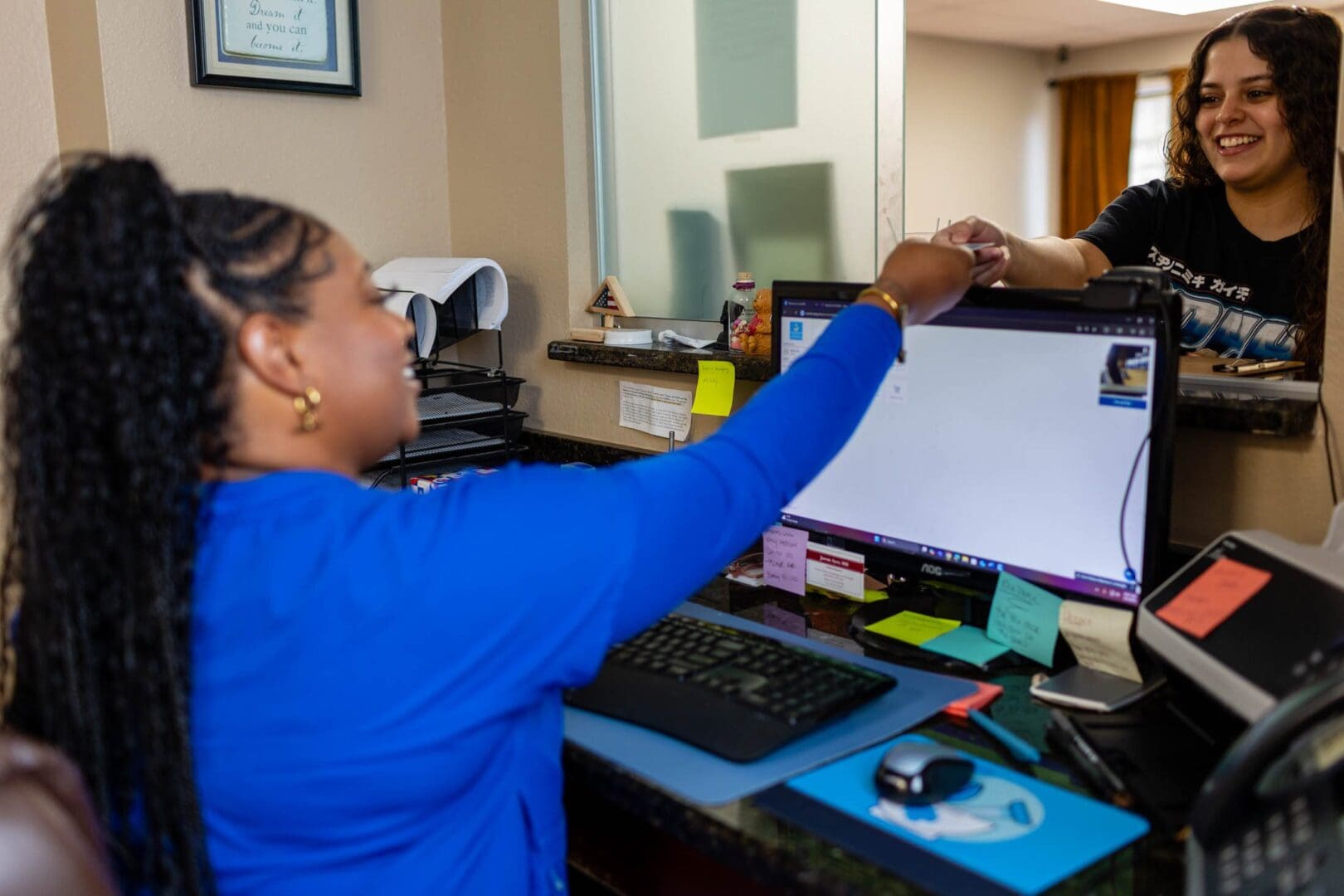 Receptionist handing paper to a smiling customer.