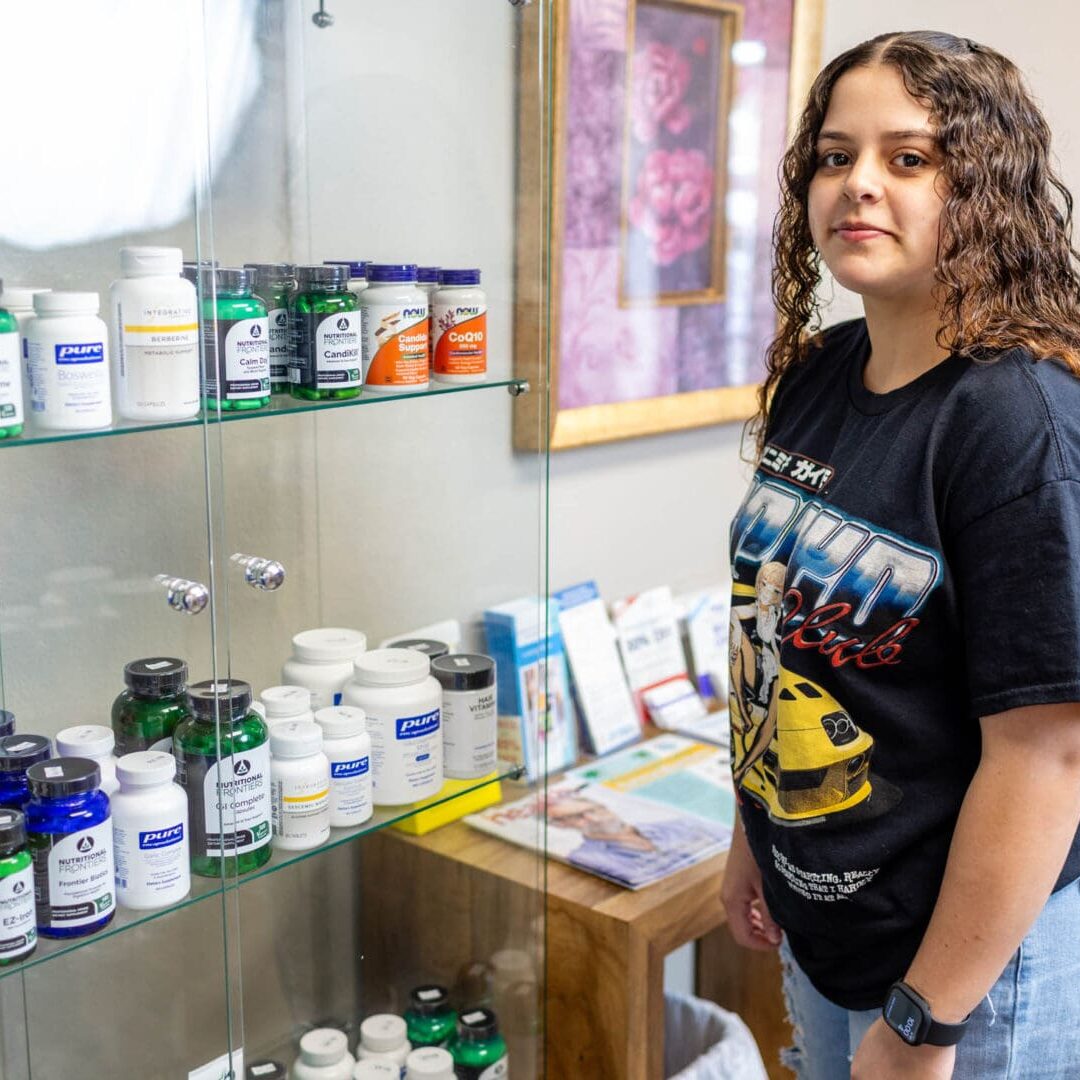 Person standing by a shelf of supplements.