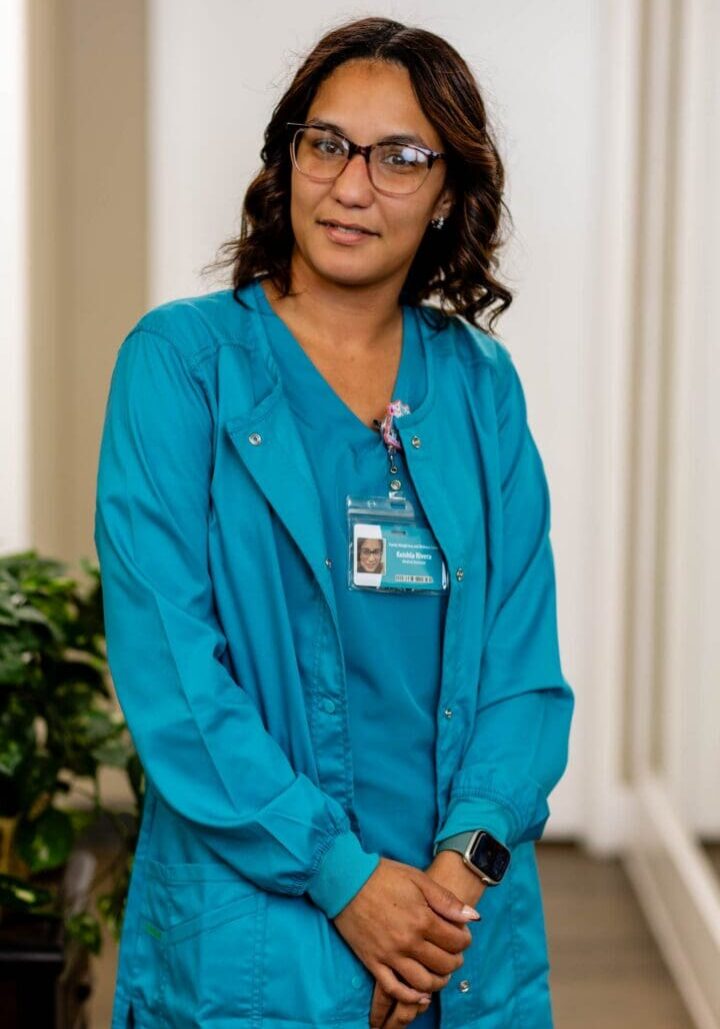Healthcare professional in blue scrubs, smiling.