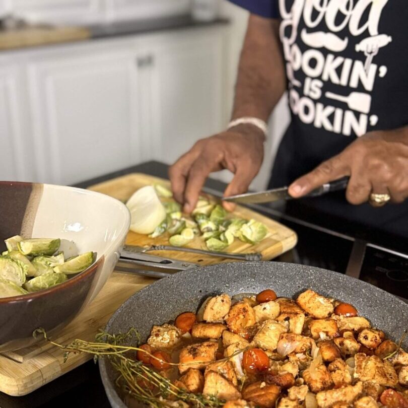 Cooking vegetables with seasoned chicken in kitchen.