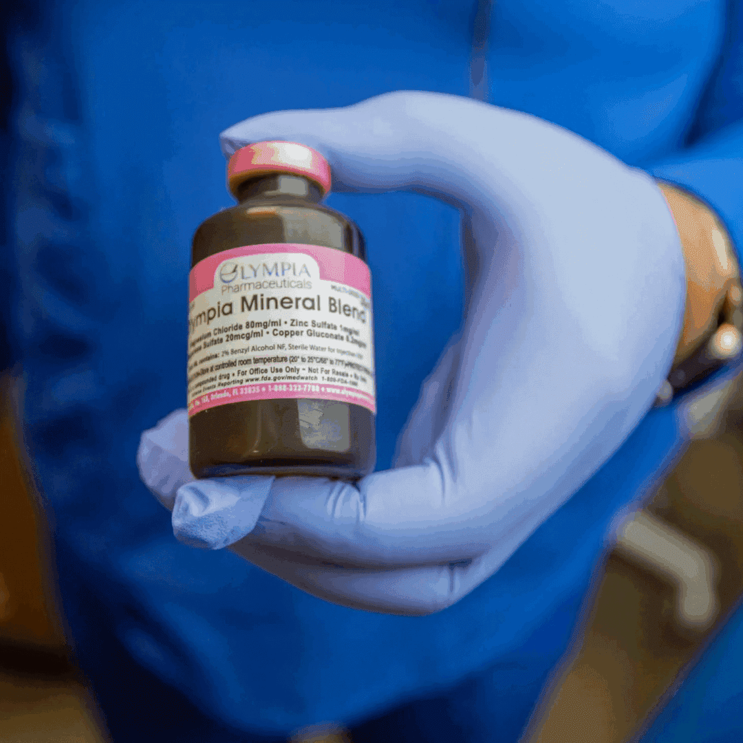 Gloved hand holding a small medical vial.