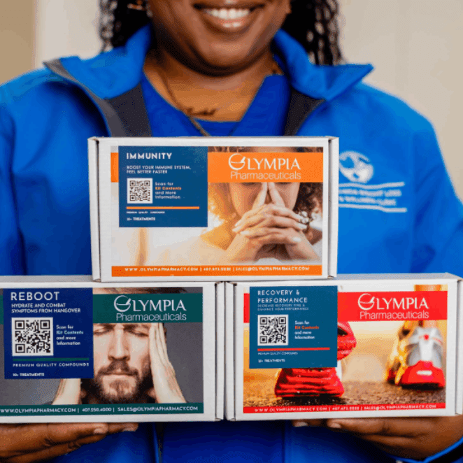Person holding three Olympia Pharmaceuticals boxes.