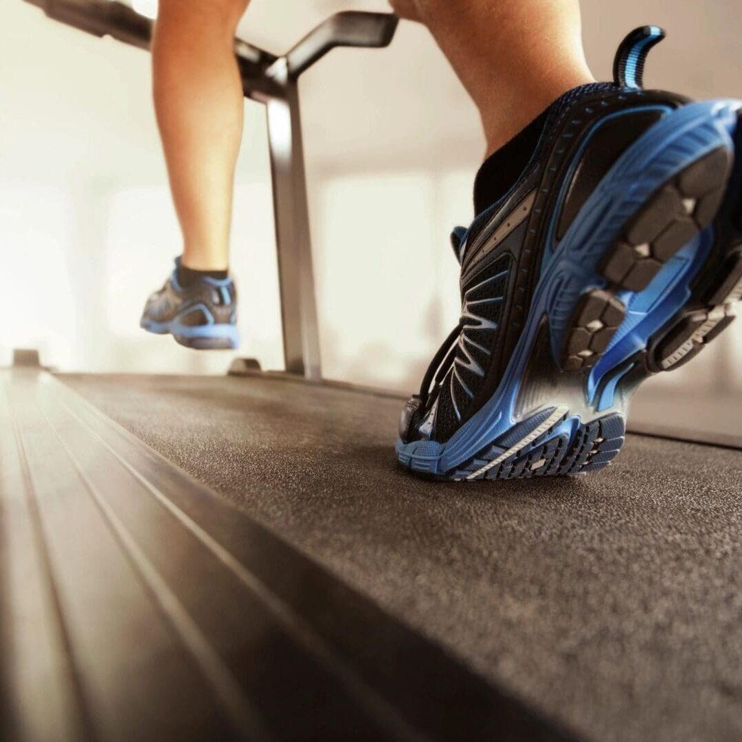 Person running on a treadmill, close-up sneakers.