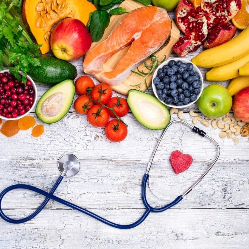 Healthy foods and stethoscope on wooden table.
